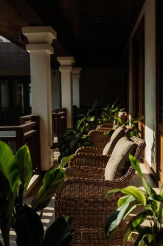 a row of wicker chairs with pillows on a porch at Athena Hotel in Pakse