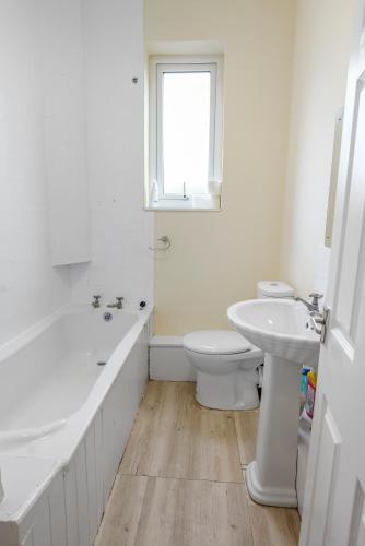 a bathroom with a tub and a toilet and a sink at Relax in Comfort 3BR Home for 6 with Full Kitchen, Lounge, Large Bath in Bury