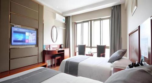 a hotel room with two beds and a flat screen tv at GreenTree Inn ChiZhou QinGYAng Miaoqian Road Rongxing Building Business Hotel in Chizhou