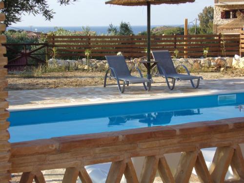 two chairs and an umbrella next to a swimming pool at Alegria Villas Complex in Vasilikos