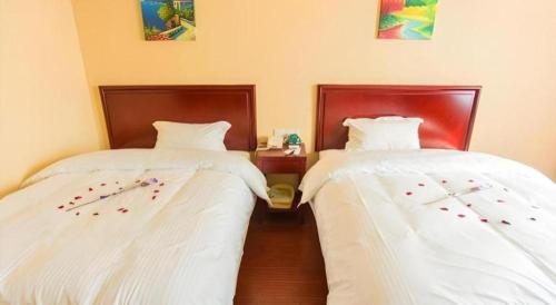 two beds sitting next to each other in a room at GreenTree Inn Taizhou New District Hospital of Renmin Hospital Mingliu Express Hotel in Jiuligou