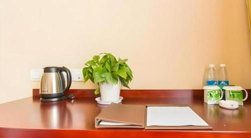 a desk with a book and a plant on it at GreenTree Inn Taizhou New District Hospital of Renmin Hospital Mingliu Express Hotel in Jiuligou