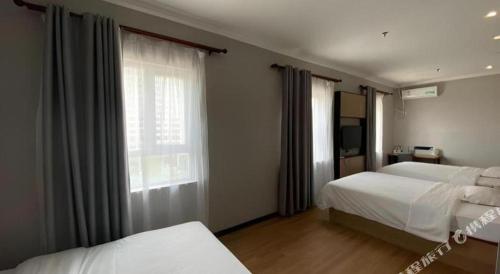 a hotel room with two beds and a window at GreenTree Inn Taizhou New District Hospital of Renmin Hospital Mingliu Express Hotel in Jiuligou