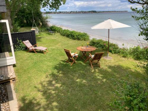 a table and chairs with an umbrella and the beach at Holiday Home By The Water In Rødvig, Stevns in Rødvig