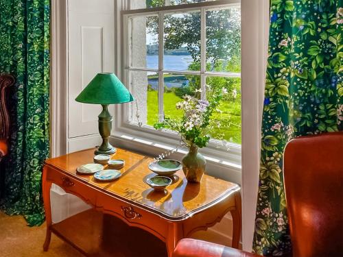a table with a lamp on it next to a window at Applecross Manse in Applecross
