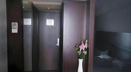a room with a door with a vase of flowers at Tianjin Juchuan Lily Hotel in Binhai