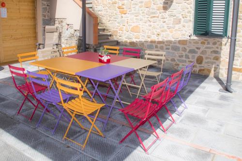 a wooden table with colorful chairs on a patio at Podere Scoglio d'Oro in Pescia
