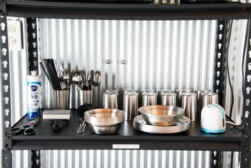 a shelf with bowls and utensils on it at Rockstar Villa 江井浜STYLE in Awaji