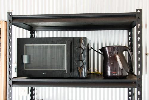 a black shelf with a microwave and a pitcher on it at Rockstar Villa 江井浜STYLE in Awaji