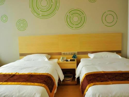a bedroom with two beds and a wooden headboard at GreenTree Inn Liaocheng Donge Culture Street Express Hotel in Liaocheng