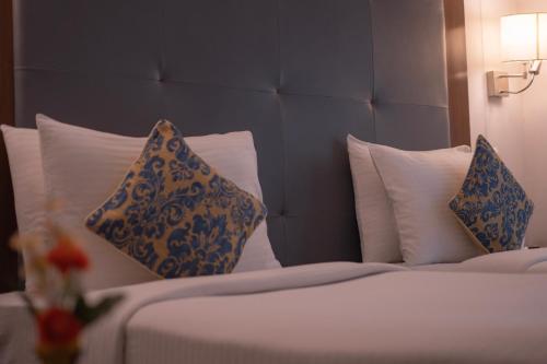 a bed with blue and white pillows on it at Hotel Clarks Collection Bhavnagar in Bhavnagar