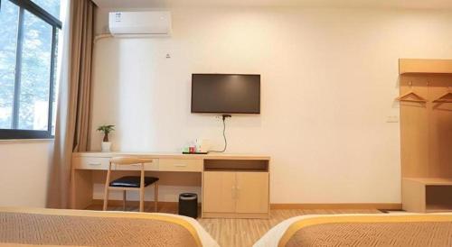 a bedroom with a desk and a tv on the wall at Shell Shanghai Jiading Nanxiang Town Minzhu Street Hotel in Shanghai
