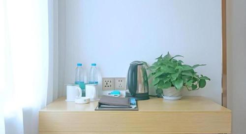 a wooden shelf with a coffee maker and a plant on it at GreenTree Inn Express Gongqing City Nanchang University in Gongqingcheng
