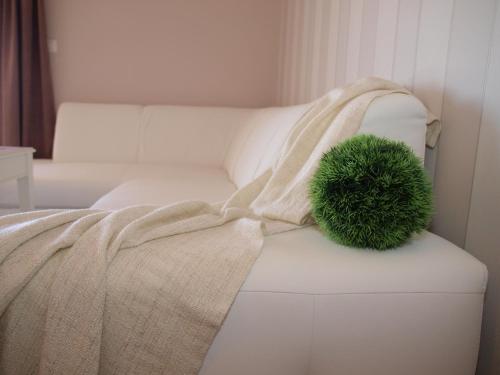 a green pillow on a white couch with a blanket at Guesthouse Olei in Malinska