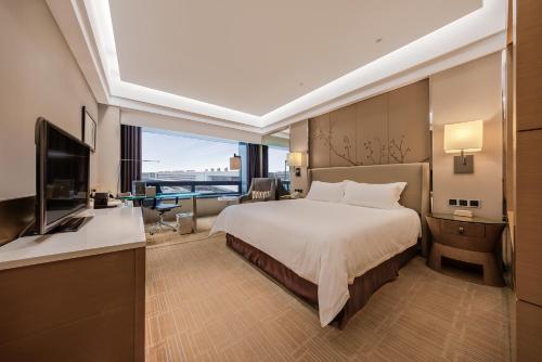 a hotel room with a bed and a television at Air China Hongqiao Airport Hotel - Air China BoYue Hotel in Shanghai