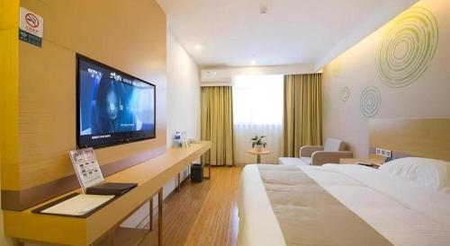 a hotel room with a large television on a wall at GreenTree Inn Beijing Shunyi Fengbo Metro Station in Beijing