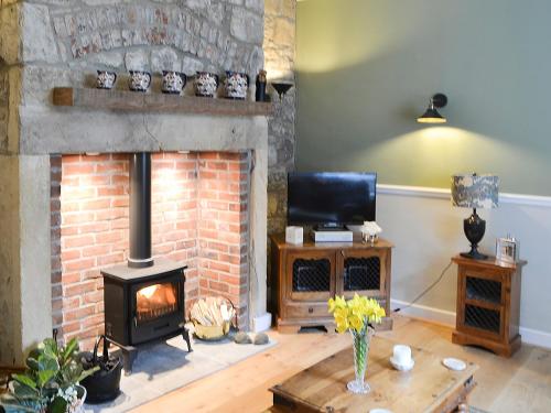 a living room with a brick fireplace and a television at Conway - Cottage in Rothbury