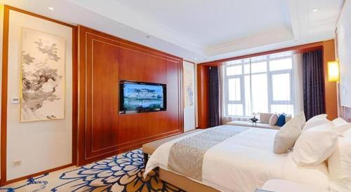 a bedroom with a large bed and a flat screen tv at YUN-RAY Hotel Shijiazhuang in Shijiazhuang