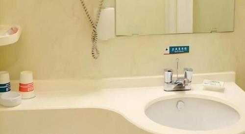 a white bathroom with a sink and a mirror at Jinjiang Inn Qingdao Wuxi Square Nanjing Road Metro Station in Qingdao