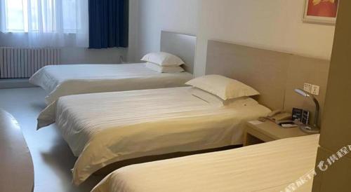 a hotel room with two beds and a telephone at Jinjiang Inn Qingdao Wuxi Square Nanjing Road Metro Station in Qingdao