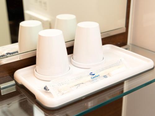 a bathroom counter with white toothbrushes and a mirror at Comfort Hotel Miyazaki in Miyazaki