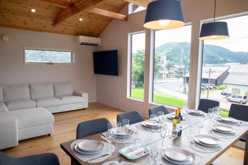 a dining room with a table and chairs and a couch at White Sierra Chalet in Hakuba