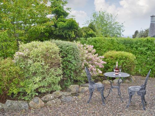 two chairs and a table in a garden at Burns Cottage in Drumnadrochit