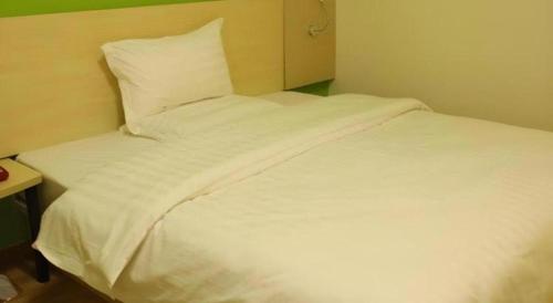 a bed with white sheets and pillows in a room at 7 Days Inn Chengdu Sichuan University South Railway Station in Chengdu