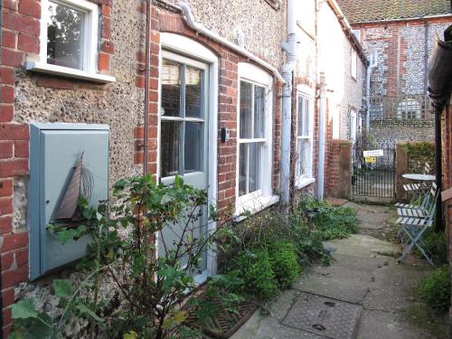 an alley with a door with a picture of a boat on it at Sea Breeze in Blakeney
