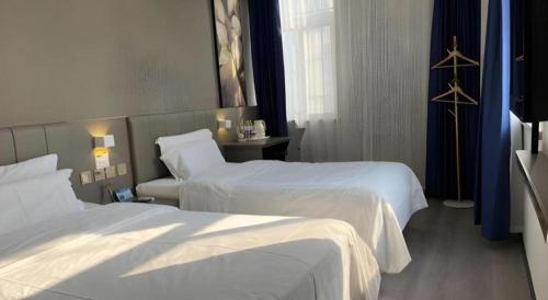 a hotel room with two beds with white sheets at 7 Days Inn Qingdao Liaoyang West Road Xinye Plaza Metro Station in Qingdao