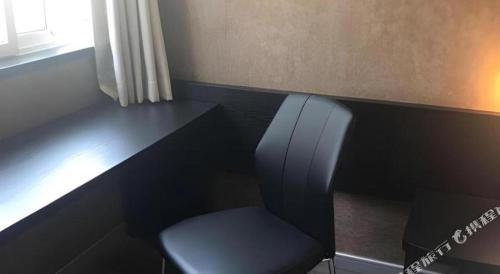 a chair sitting next to a desk with a window at 7 Days Inn Qingdao Liaoyang West Road Xinye Plaza Metro Station in Qingdao