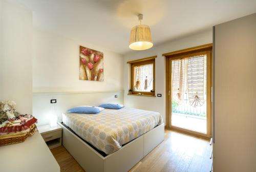 Un dormitorio con una cama con almohadas azules y una ventana en Le Case del Ponte, en Villa di Tirano