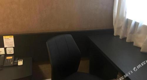 a black desk with a chair and a telephone at 7 Days Inn Qingdao Liaoyang West Road Xinye Plaza Metro Station in Qingdao