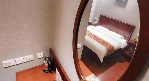 a reflection of a bedroom with a bed in a mirror at GreenTree Inn Suzhou Shihu Suli Road Express Hotel in Suzhou