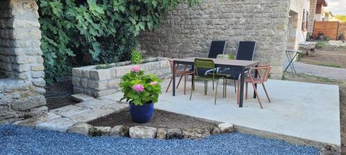 a patio with a table and chairs and a plant at 2 Gites dans les remparts à Dun sur Meuse in Dun-sur-Meuse