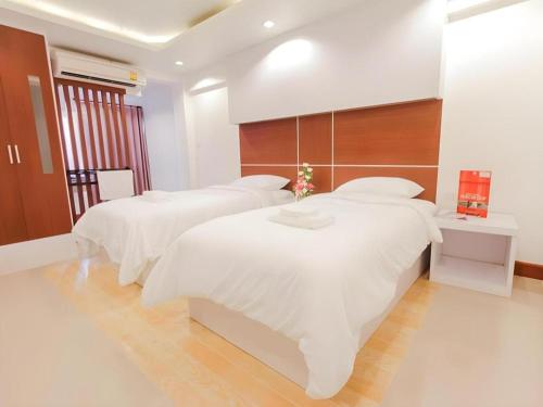 a bedroom with two beds with white sheets at Orchid Residence in Nakhon Si Thammarat