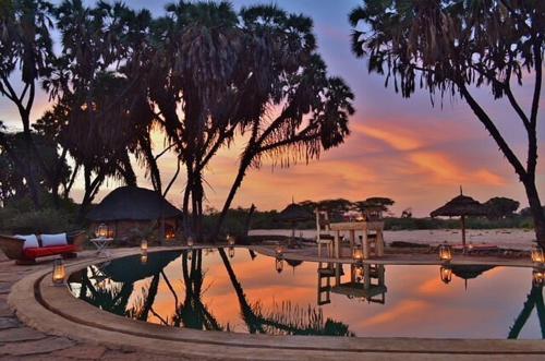 a pool of water with trees and a sunset at Saruni Rhino in Kauro