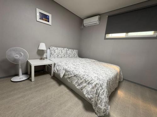 a bedroom with a bed and a desk with a fan at Gyeongju BonghwangMansion in Gyeongju