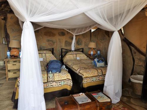 a bedroom with two beds and a canopy at Saruni Rhino in Kauro