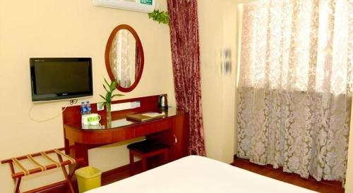 a bedroom with a bed and a tv and a mirror at GreenTree Inn Hefei Chenghuangmiao San Xiao Kou Subway Station Hotel in Hefei