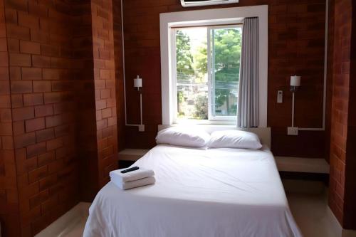 two beds in a room with a window at Changsova Hotel in Rayong