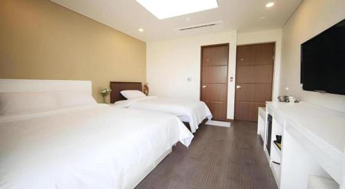 a bedroom with two beds and a flat screen tv at Sea View Hotel in Jeju
