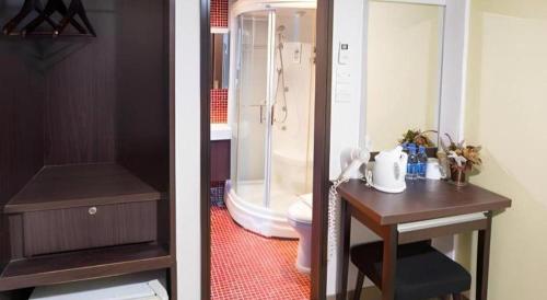 a bathroom with a shower and a table with a sink at Metroplace Olympic in Hong Kong