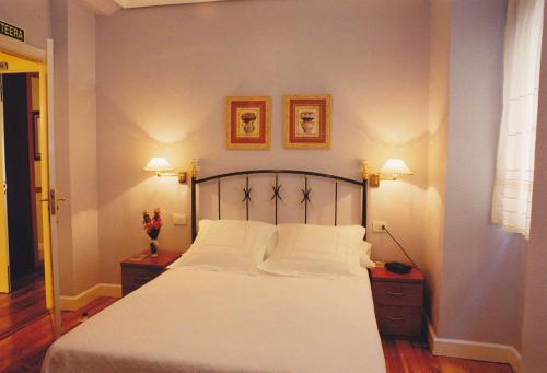 a bedroom with a large white bed with two lamps at Torre Ercilla Ostatua in Bermeo