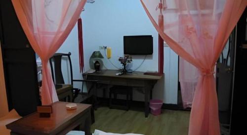 a room with a desk and a window with pink curtains at Pingyao Yufengheng Hotel in Pingyao
