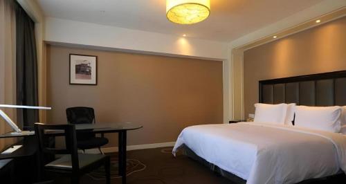 a hotel room with a bed and a desk and a table at Jinjiang Metropolo Hotel Classiq YMCA People Square in Shanghai