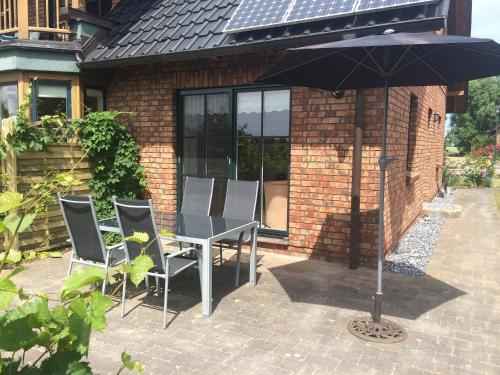 a table and chairs with an umbrella in front of a house at Fewo Lukas in Polchow