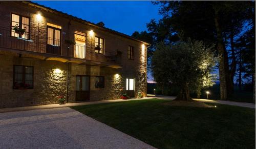 a building with a tree in the front yard at night at Casale San Galgano in Chiusdino