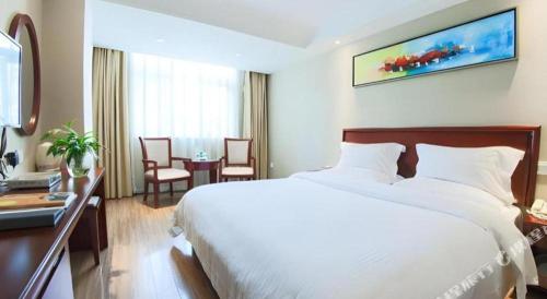 a hotel room with a large bed and a table at GreenTree Inn Nanning Langdong Hotel in Nanning