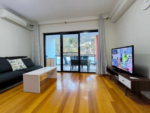 a living room with a couch and a flat screen tv at Comfy 2-bedroom 2-balcony apartment Close to CBD, Train and Metro easy reach in Sydney